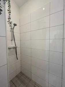 a bathroom with a shower with white tiled walls at De Zeebries in Warmenhuizen +8 photos