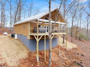 a house with a wrap around deck in the woods at Hilltop Haven Treehouse in Cornelia