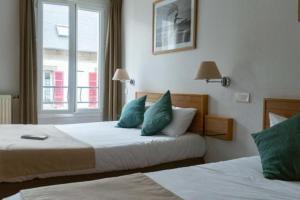 a hotel room with two beds and a window at Hotel les voyageurs in Saint-Renan