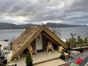 a house with two chairs on a deck next to the water at Småstranda 7B Boathouse in Store Teisten