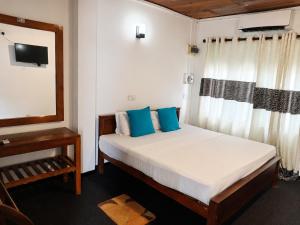 a bedroom with a bed with blue pillows and a mirror at Villa Yuvin in Matara +26 photos