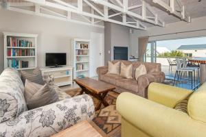 a living room with two couches and a tv at Spatalla Holiday Homes in Kleinmond