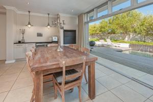 a kitchen and dining room with a wooden table and chairs at Spatalla Holiday Homes in Kleinmond