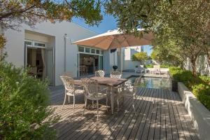a wooden deck with a table and chairs and an umbrella at Spatalla Holiday Homes in Kleinmond