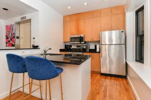 a kitchen with a stainless steel refrigerator and blue bar stools at Elegant FiDi 3BR Condo - Private Elevator - Modern Luxury in New York
