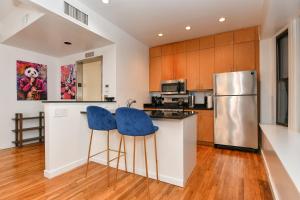 a kitchen with a refrigerator and two blue bar stools at Elegant FiDi 3BR Condo - Private Elevator - Modern Luxury in New York +22 photos