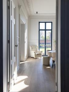 a hallway with a living room with a chair and a table at Statig herenhuis met grote tuin en jacuzzi in Geetbets