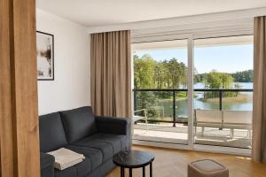 a living room with a couch and a large window at Ruciane Residence in Ruciane-Nida