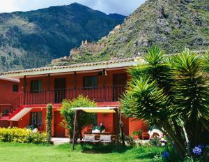una casa rossa con una montagna sullo sfondo di LILIUM VALLEY a Ollantaytambo Altre 54 foto