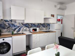 a kitchen with white cabinets and a washing machine at Casa Giorgia with Parking Space in Genoa