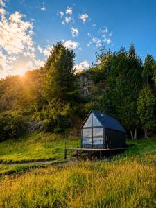 a glass house in a field with the sun in the background at Basecamp Colombia in Carmen de Carupa