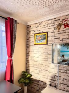 a room with a brick wall with a red curtain at Serenity Homes in Ruiru