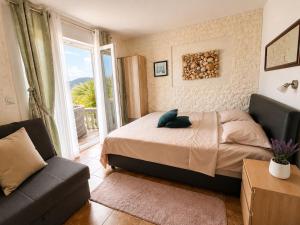 a bedroom with a bed and a couch and a window at Apartments Obradovic in Krašići +60 photos