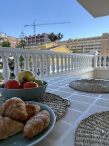 a table with a bowl of fruit and pastries on a balcony at Alpen 1 Voramar Playa Norte in Peniscola