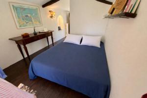 a bedroom with a blue bed and a desk at La chambre du Mazet in Fayence