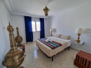 a bedroom with a bed and blue curtains at Plage El Haouzia in El Jadida +61 photos