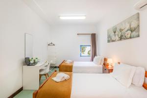 a hotel room with two beds and a desk at HI Faro – Pousada de Juventude in Faro