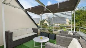 a balcony with a couch and chairs and a table at Chambre calme avec petit déjeuner in Gévezé