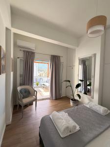 a bedroom with a bed and a chair and a window at Sitia Heights Apartment - Central Sea View in Sitia