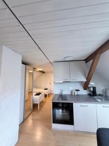 a kitchen with white cabinets and a living room at Top-floor apartment for up to 3 guests in Dreieich