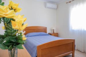 a bedroom with a bed and a vase with yellow flowers at Villa BelaVista with Private Pool in Ferragudo +66 photos
