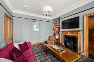 a living room with a pink couch and a fireplace at Heywood Cottage in St. Andrews +16 photos