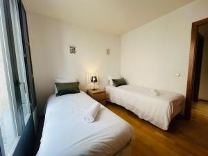 two beds in a room with white walls and wood floors at Two bedroom apartment behind the Rambla in Girona +4 photos