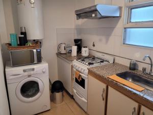 a small kitchen with a stove and a washing machine at Alto Valle Home in Cipolletti