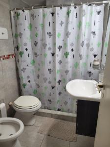 a bathroom with a shower curtain with a toilet and a sink at Alto Valle Home in Cipolletti