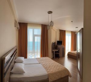 a bedroom with a bed and a desk with a computer at Hotel Lazuri in Kvariati