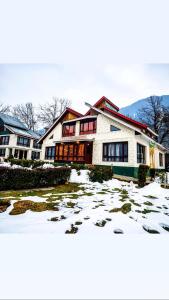 a large white house with snow on the ground at Hotel alpine resort pahalgam in Pahalgām