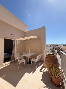 a patio with a table and chairs and an umbrella at Sitia Heights Apartment - Central Sea View in Sitia +13 photos