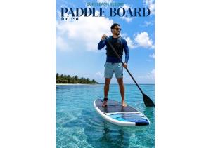 a man standing on a paddle board in the water at Suki Beach Resort Beachfront Cottage in Santa Magdalena