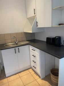 a kitchen with white cabinets and a sink at Comfort & Convenience in Edenvale +5 photos