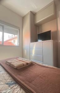 a bedroom with a bed with a flat screen tv at Apto familiar, 150mts do mar, completo e aconchegante em Palmas in Governador Celso Ramos