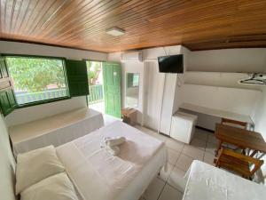 a room with a bed and a table and a window at Pousada Tapuia in Porto Seguro