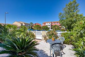a patio with a table and chairs in a garden at Gîtes Villa Beau Soleil Agde in Agde