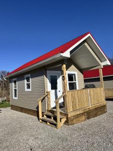 ein kleines Haus mit rotem Dach und Veranda in der Unterkunft Gros Morne Tiny Chalets in Rocky Harbour