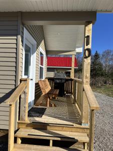 eine Veranda mit zwei Stühlen und einem Grill an einem Haus in der Unterkunft Gros Morne Tiny Chalets in Rocky Harbour