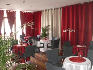 サン・マロにあるアルファ オーシャンのテーブルと椅子、赤いカーテンが備わる部屋