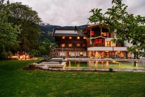 a large house with a pond in front of it at Zillertaler Hofchalets Schustererhof in Stumm