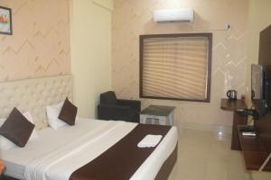 a bedroom with a bed with a chair and a window at Triple Tree Hotels and Resorts in Bhubaneshwar +4 photos