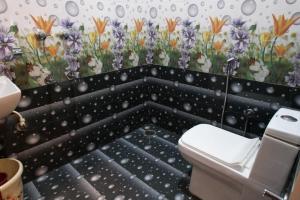 a bathroom with a toilet and flowers on the wall at Unique3 in Yercaud