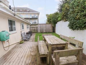 a wooden deck with a table and bench in a yard at The Bungalow in Pwllheli