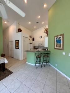 a kitchen with green walls and a table and stools at Right Direction Rentals Carnoustie Townhome in Port Saint Lucie