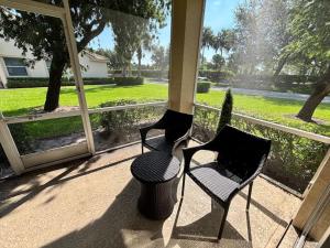 two chairs and a table on a screened in porch at Right Direction Rentals Carnoustie Townhome in Port Saint Lucie +15 photos