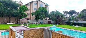 a building with a swimming pool in front of a house at Apartment on doonside Beach in Kingsborough