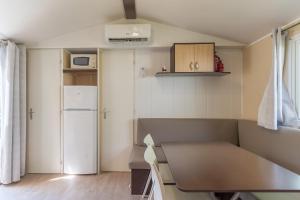 a small kitchen with a refrigerator and a table at Mobil-home Le 154 aux Iscles in La Roque-dʼAnthéron