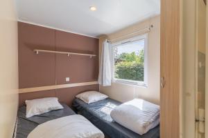 two beds in a small room with a window at Mobil-home Le 154 aux Iscles in La Roque-dʼAnthéron