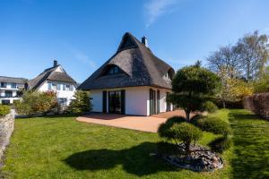 a house with a thatched roof with a tree in the yard at Ferienhaus Seeadler 3 in Fuhlendorf